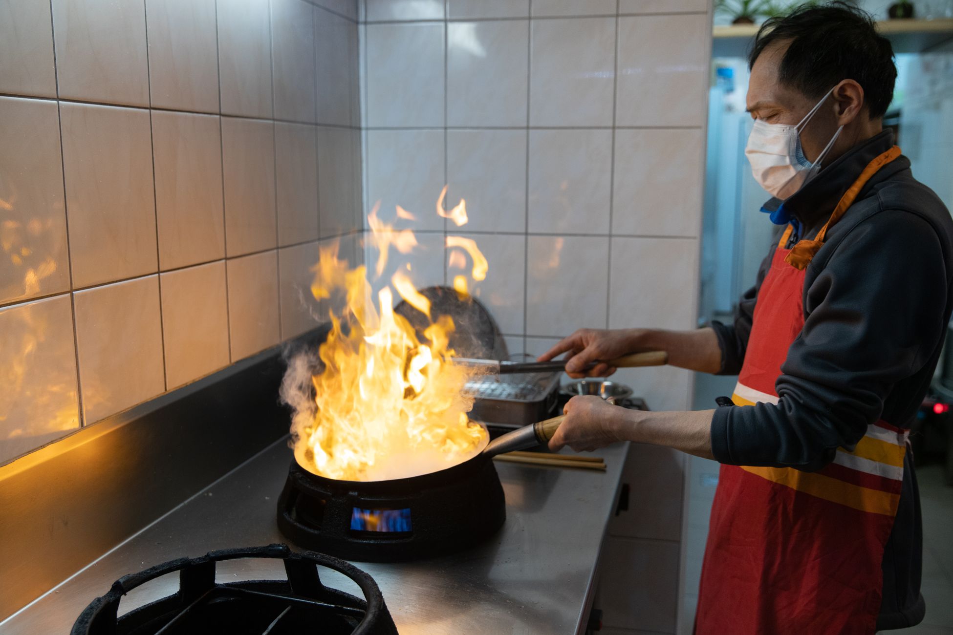 厨师在猛火灶上用大炒锅进行爆炒,火焰升腾