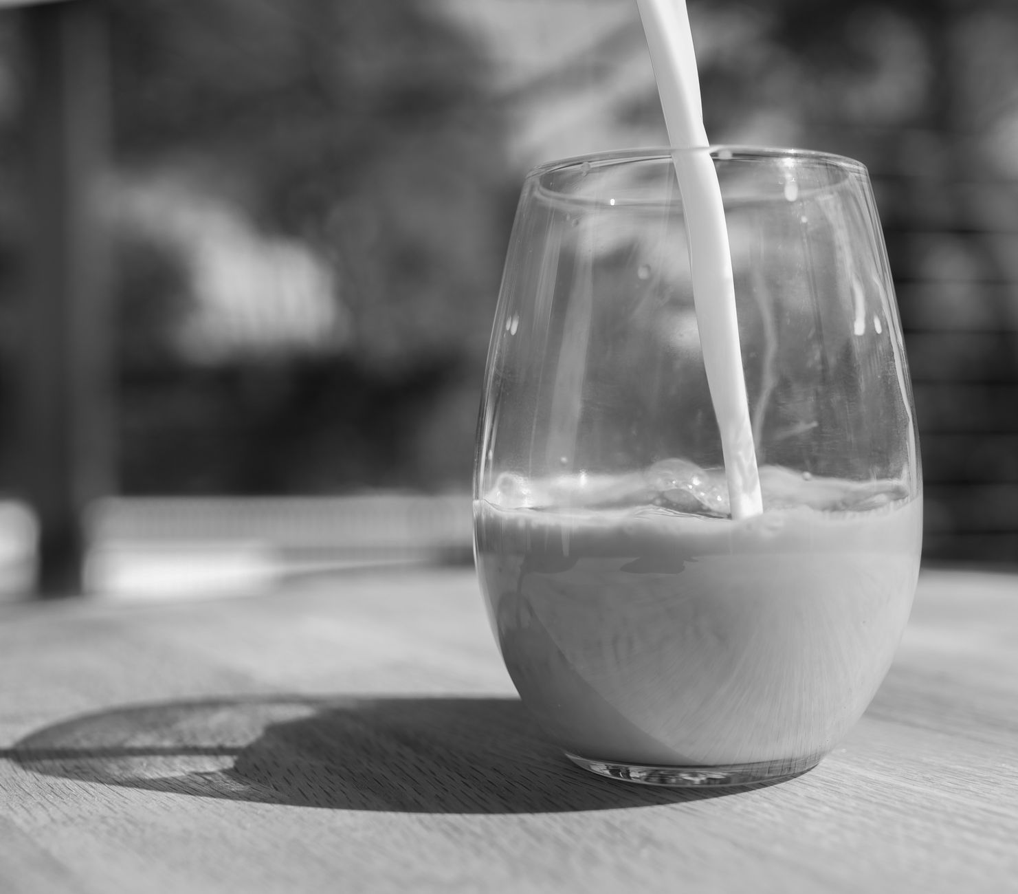 牛奶倒入透明玻璃杯中,呈现乳白色液体状态
